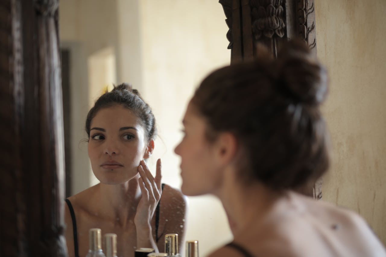 Mujer reflexionando frente al espejo por manchas en la piel causadas por el sol y el tiempo Melasma y manchas faciales cómo recuperar tu piel.
